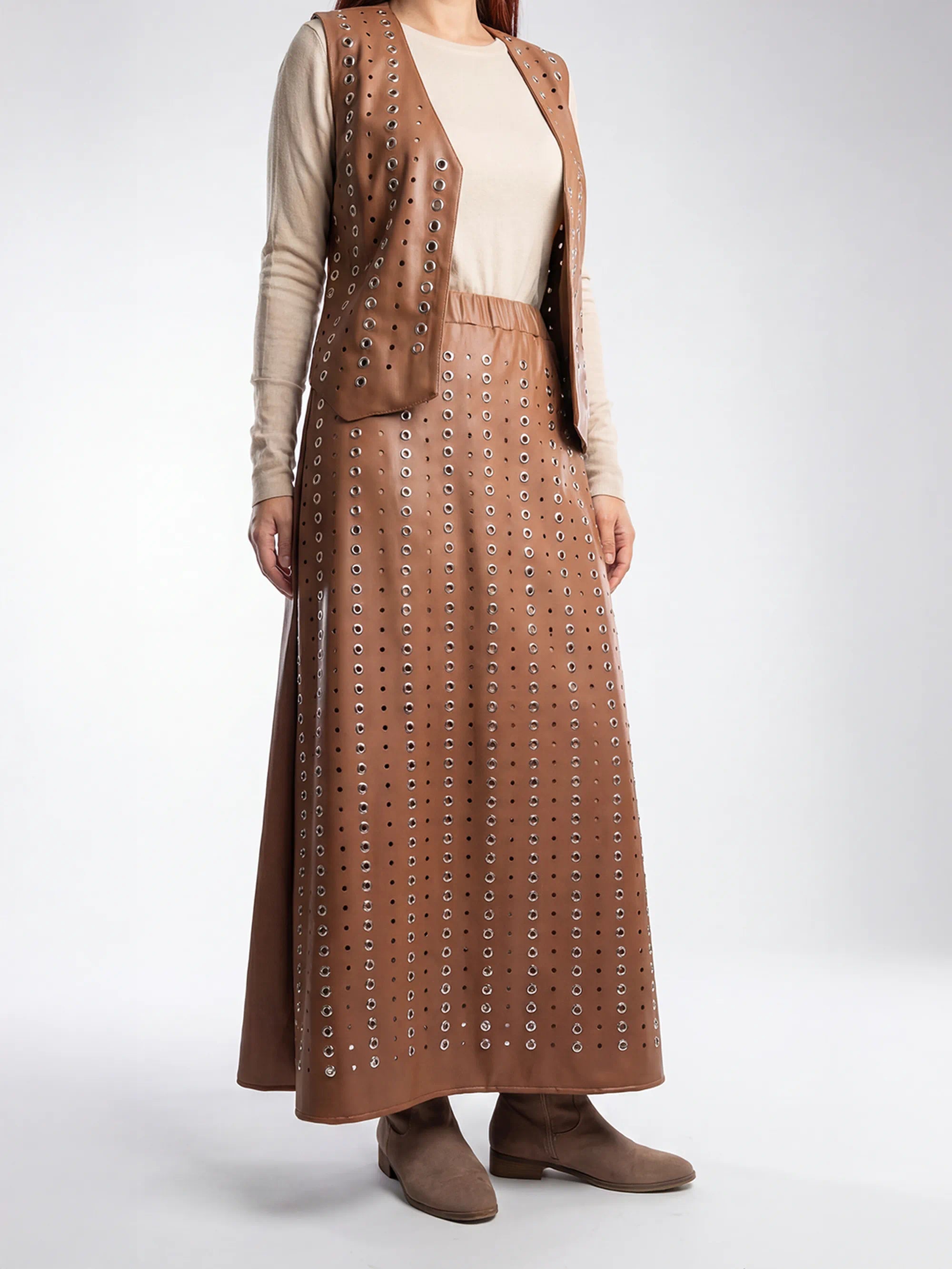 Person wearing a brown leather outfit with a vest and skirt on a white background