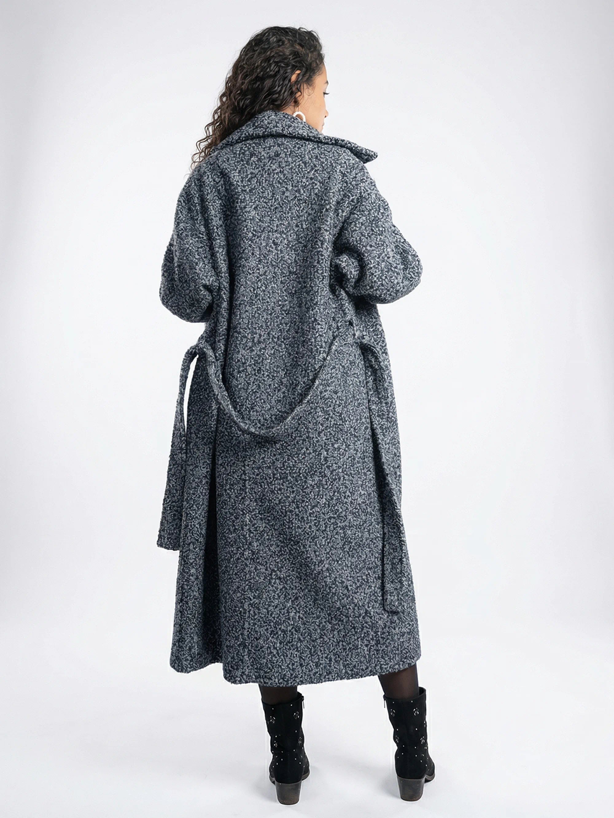 Person wearing a long gray coat on a white background