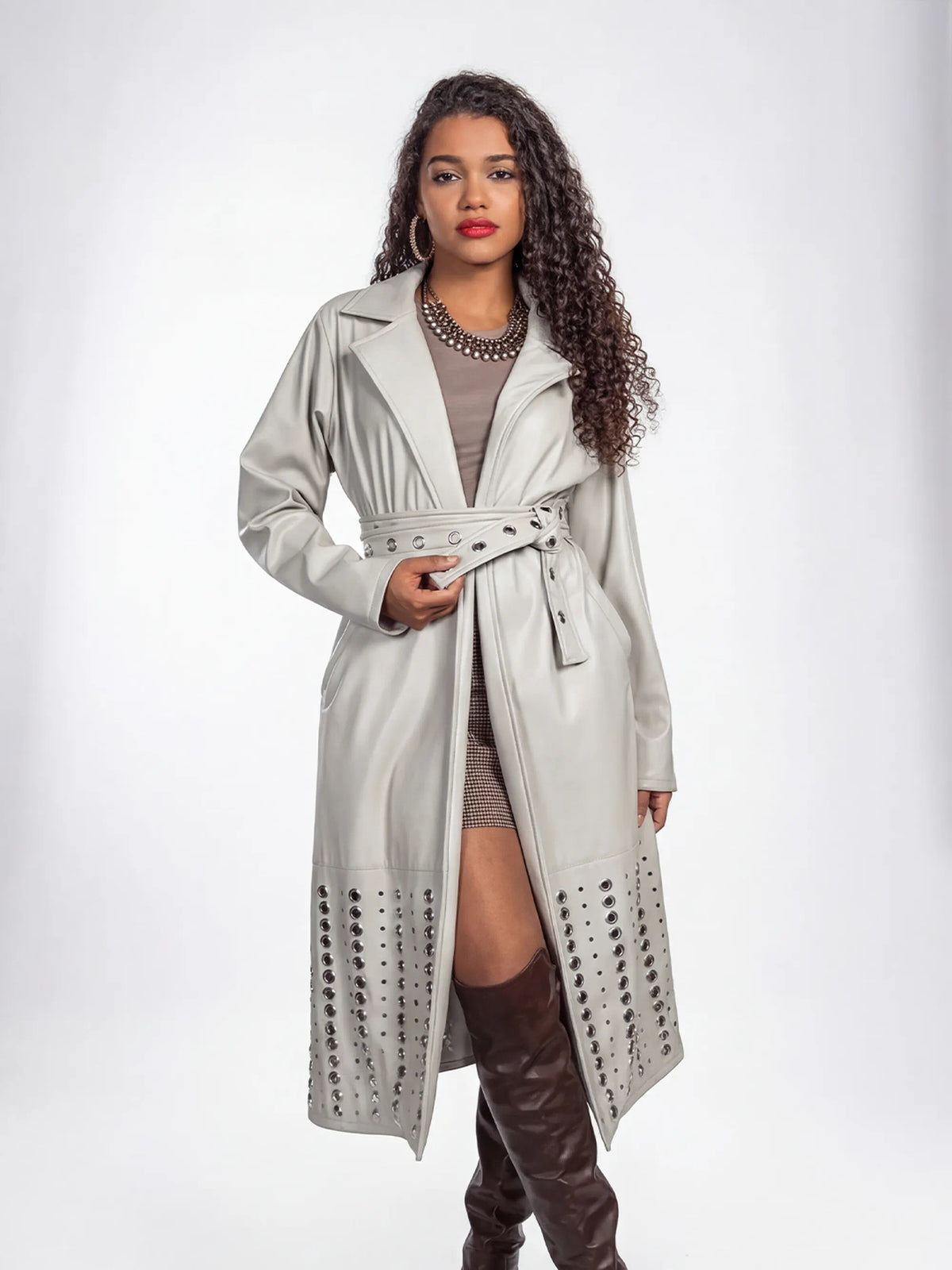 Woman wearing a light gray trench coat with a belt on a white background