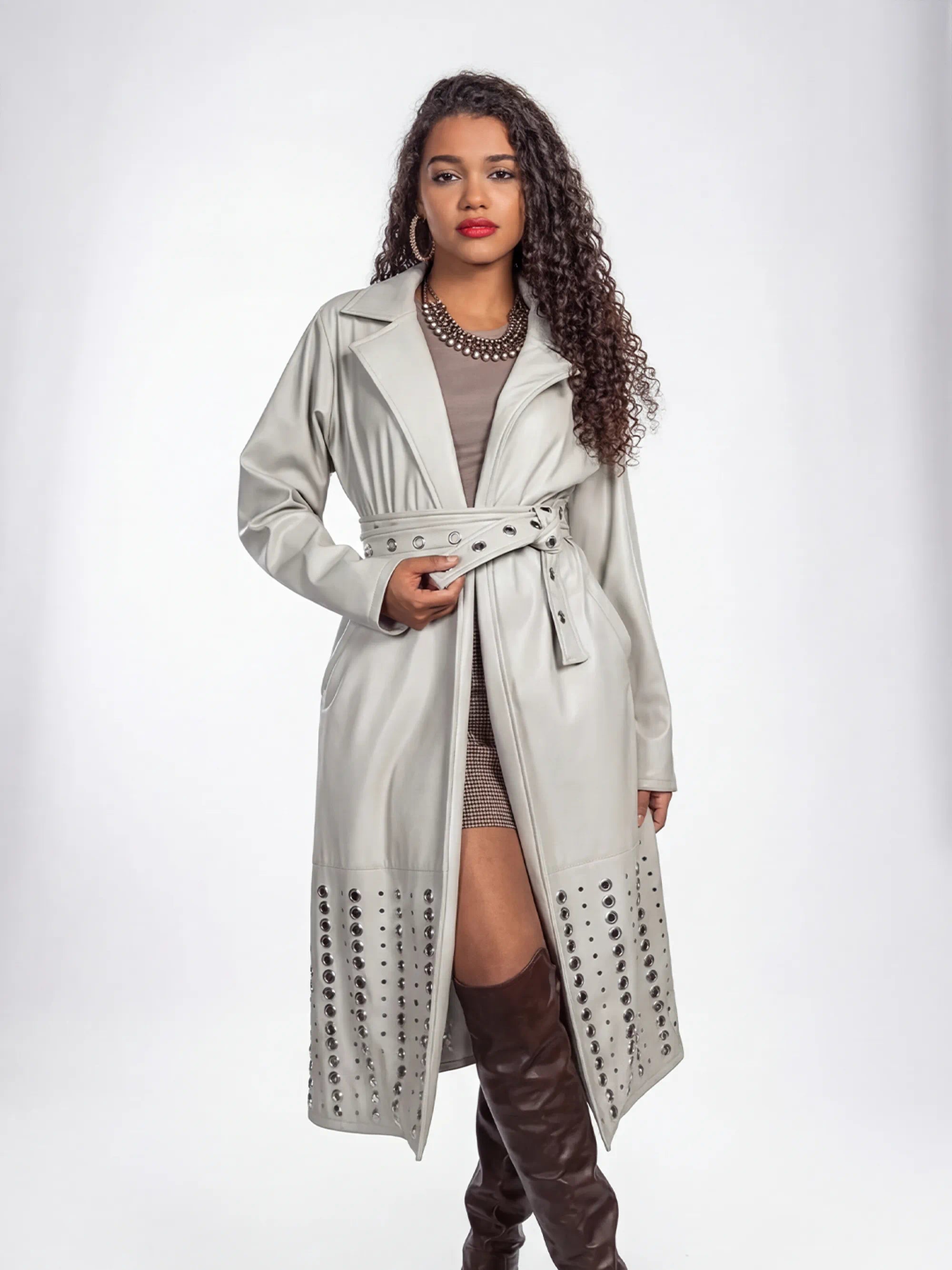 Woman wearing a light gray trench coat with a belt on a white background