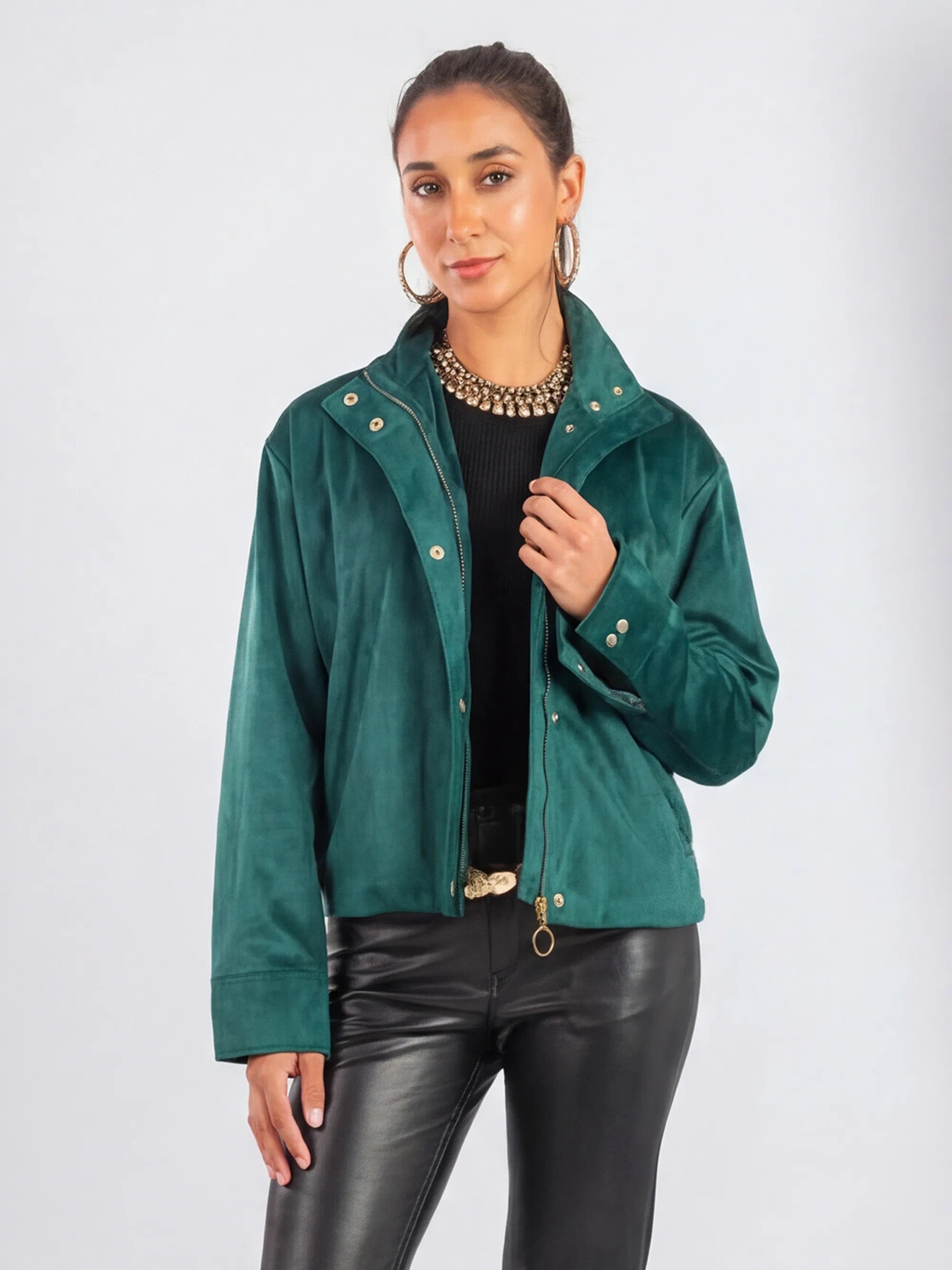 Woman wearing a green jacket and black pants on a white background