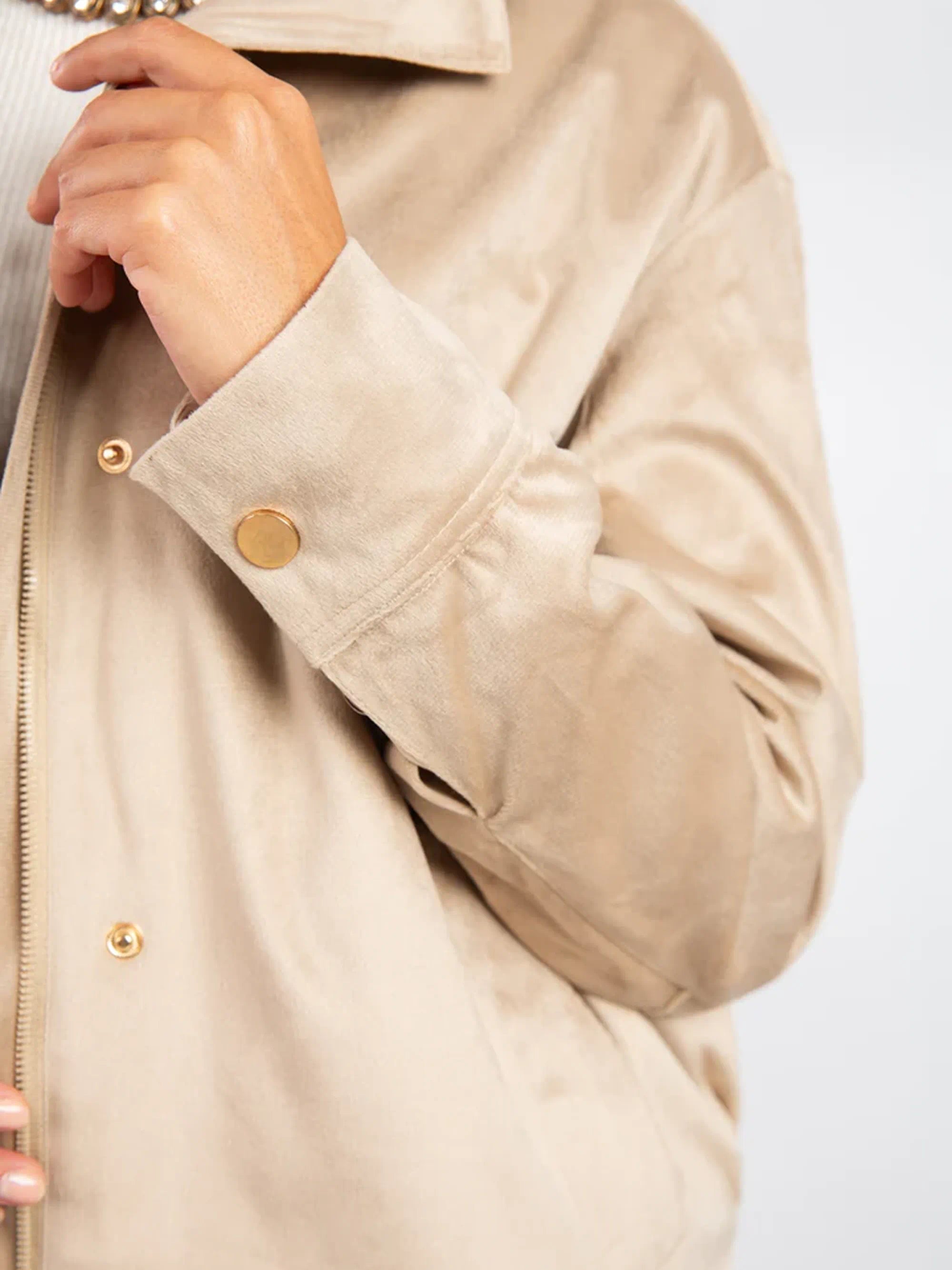 Close-up of a beige jacket with gold buttons on a white background