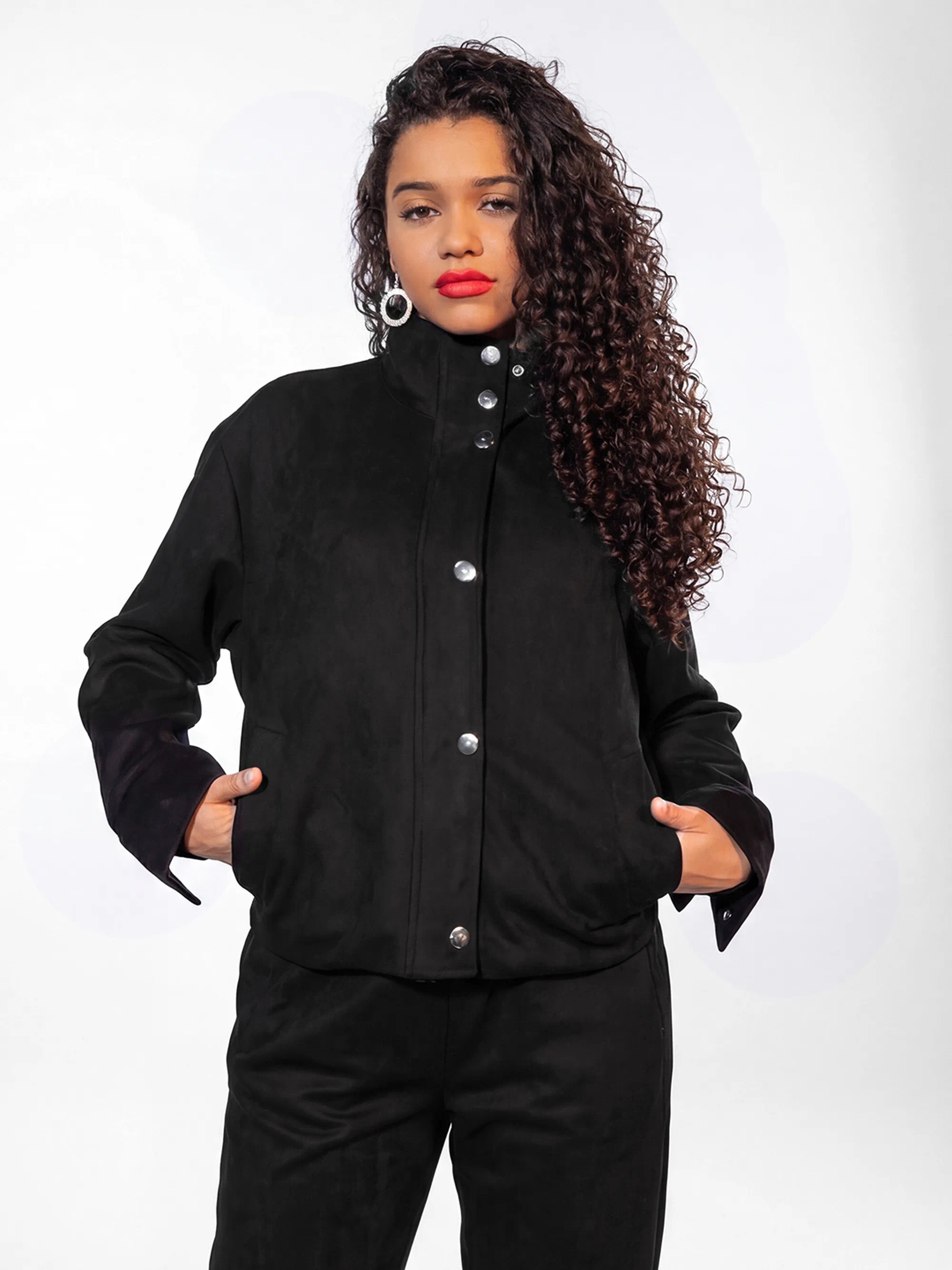 Woman wearing a black jacket with silver buttons on a white background