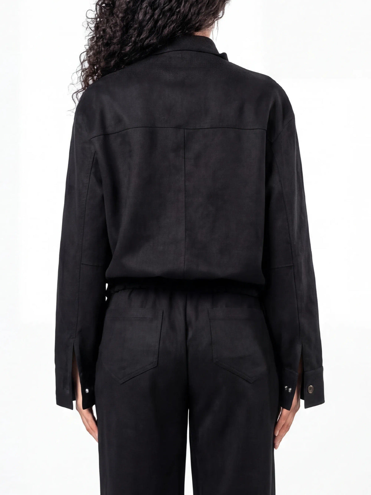 Person wearing a black outfit with a jacket and pants on a white background