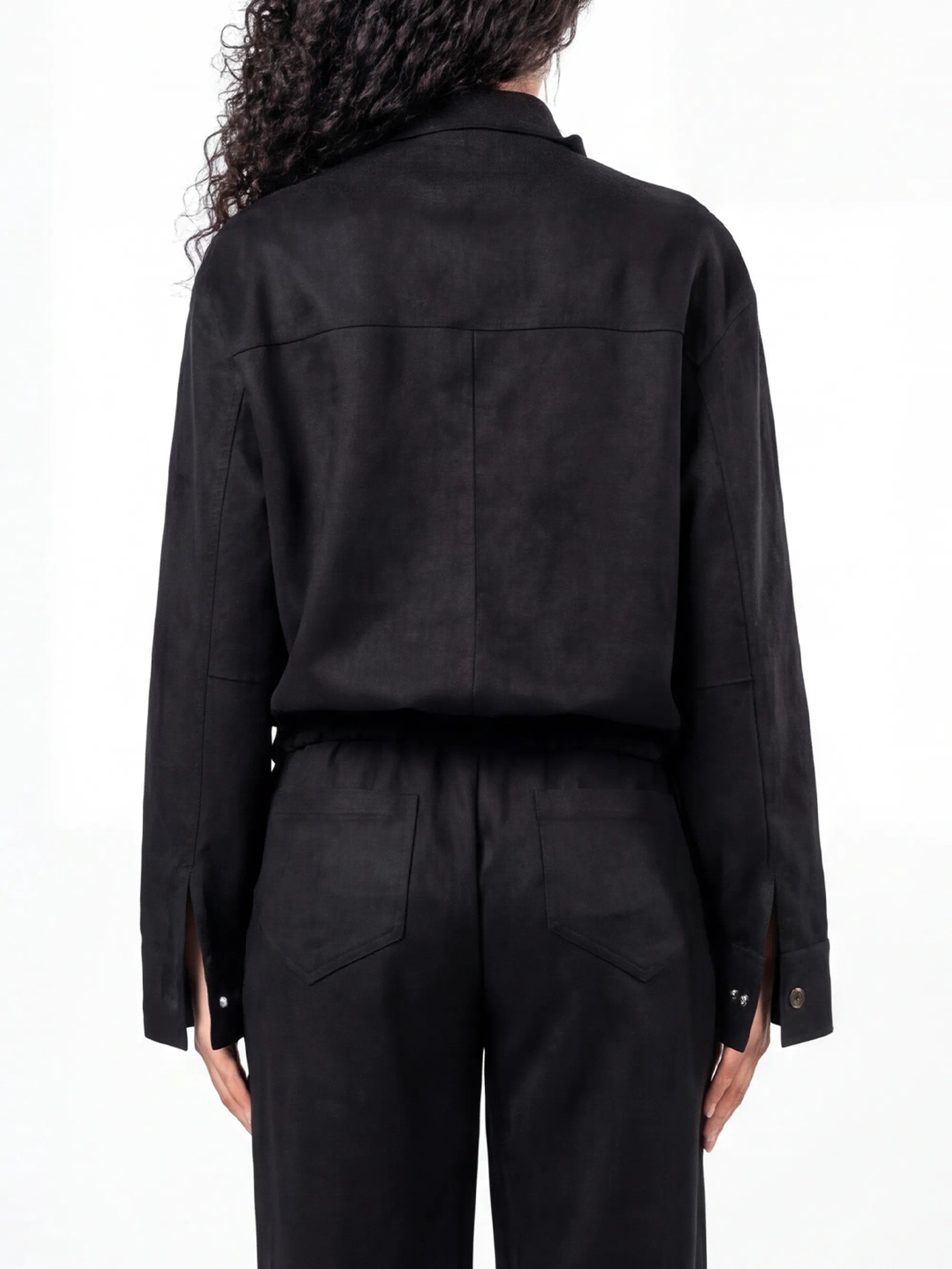 Person wearing a black outfit with a jacket and pants on a white background