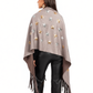 Woman wearing a beige poncho with star patterns and fringes on a white background