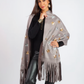 Woman wearing a gray fringe scarf with butterfly patterns on a white background