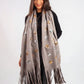 Woman wearing a gray scarf with star patterns and fringes on a white background
