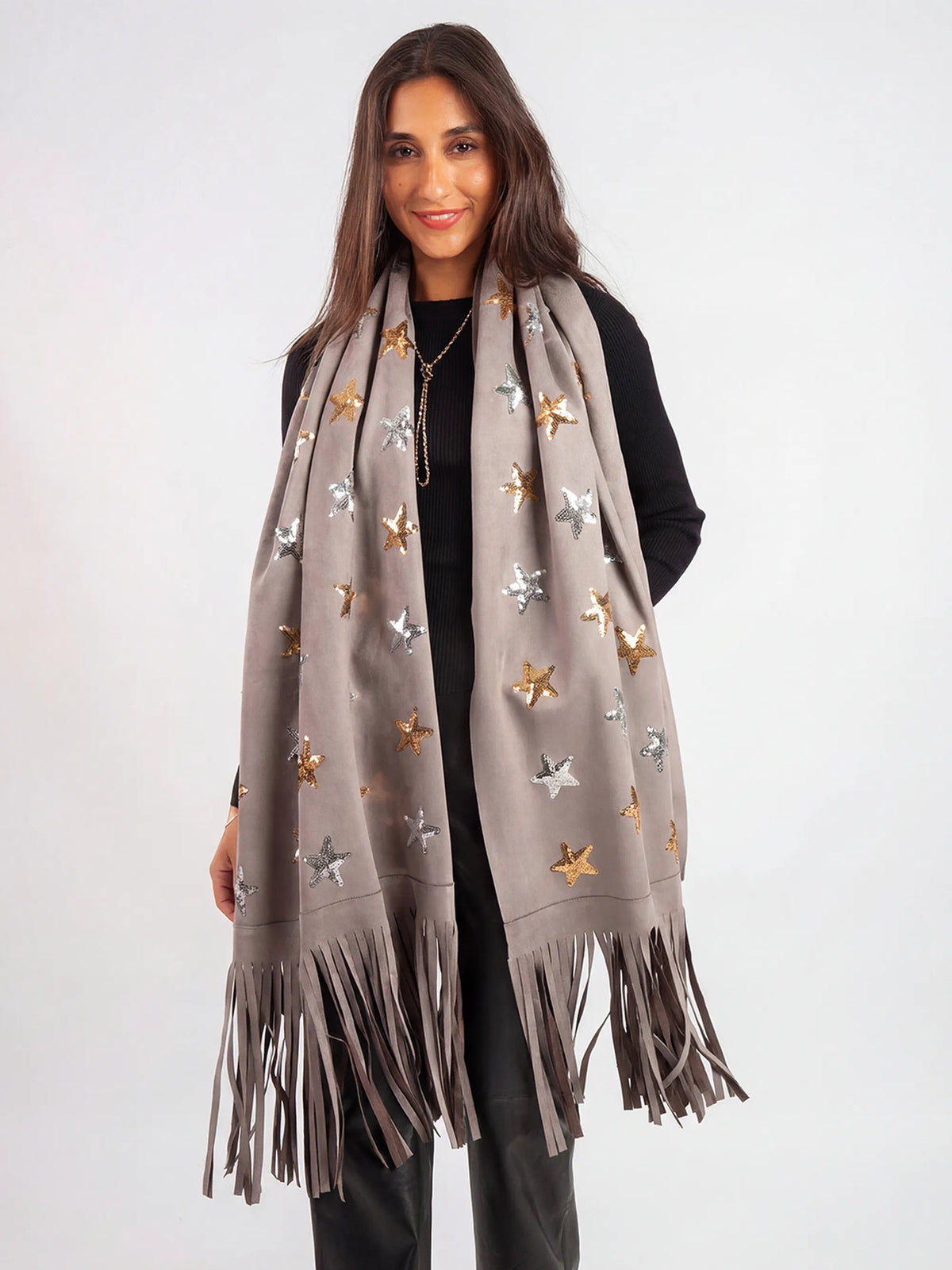 Woman wearing a gray scarf with star patterns and fringes on a white background