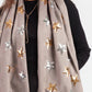 Gray scarf with star patterns worn by a person on a white background