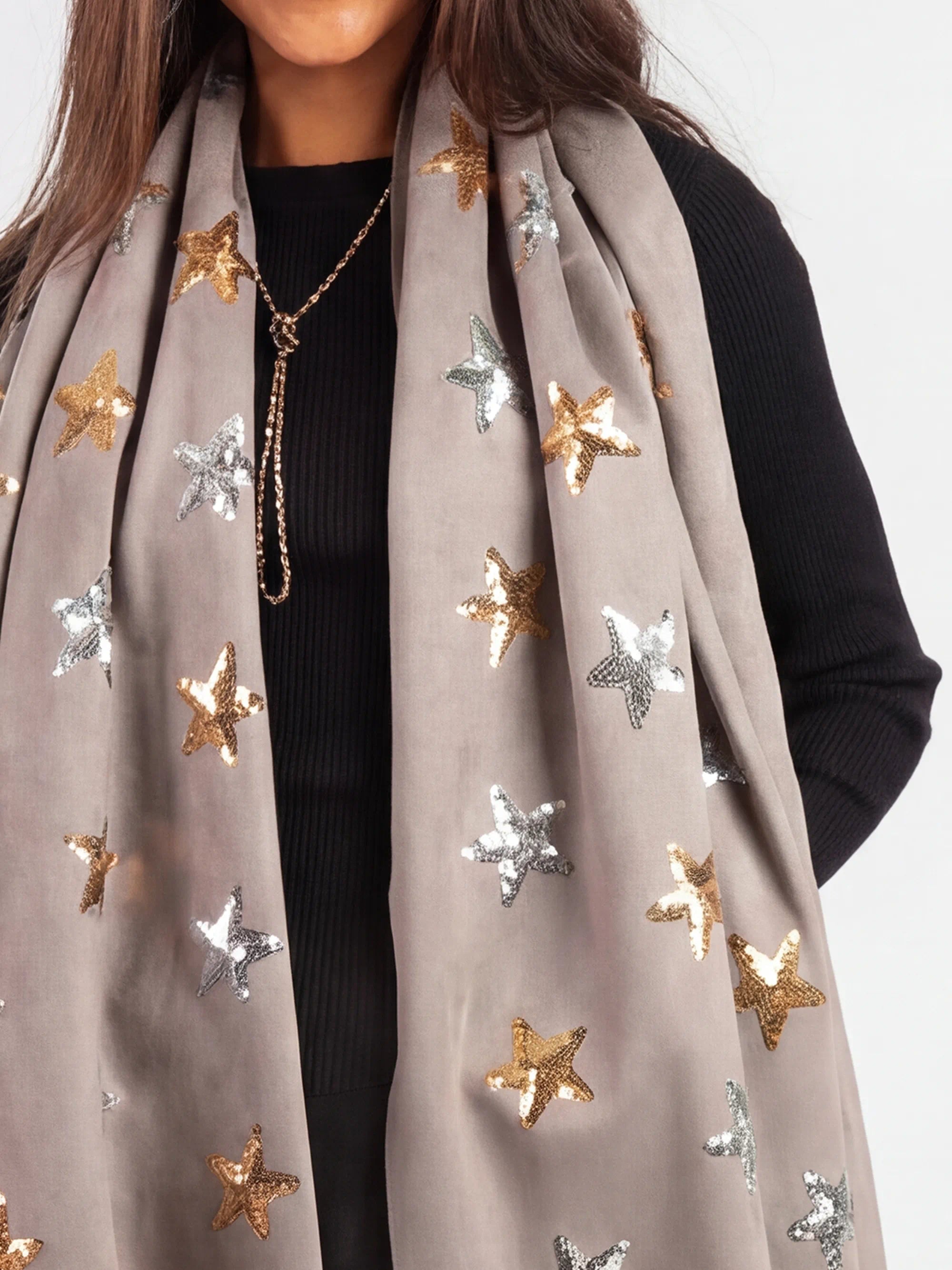 Gray scarf with star patterns worn by a person on a white background