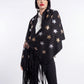 Woman wearing a black star-patterned poncho with fringe on a white background