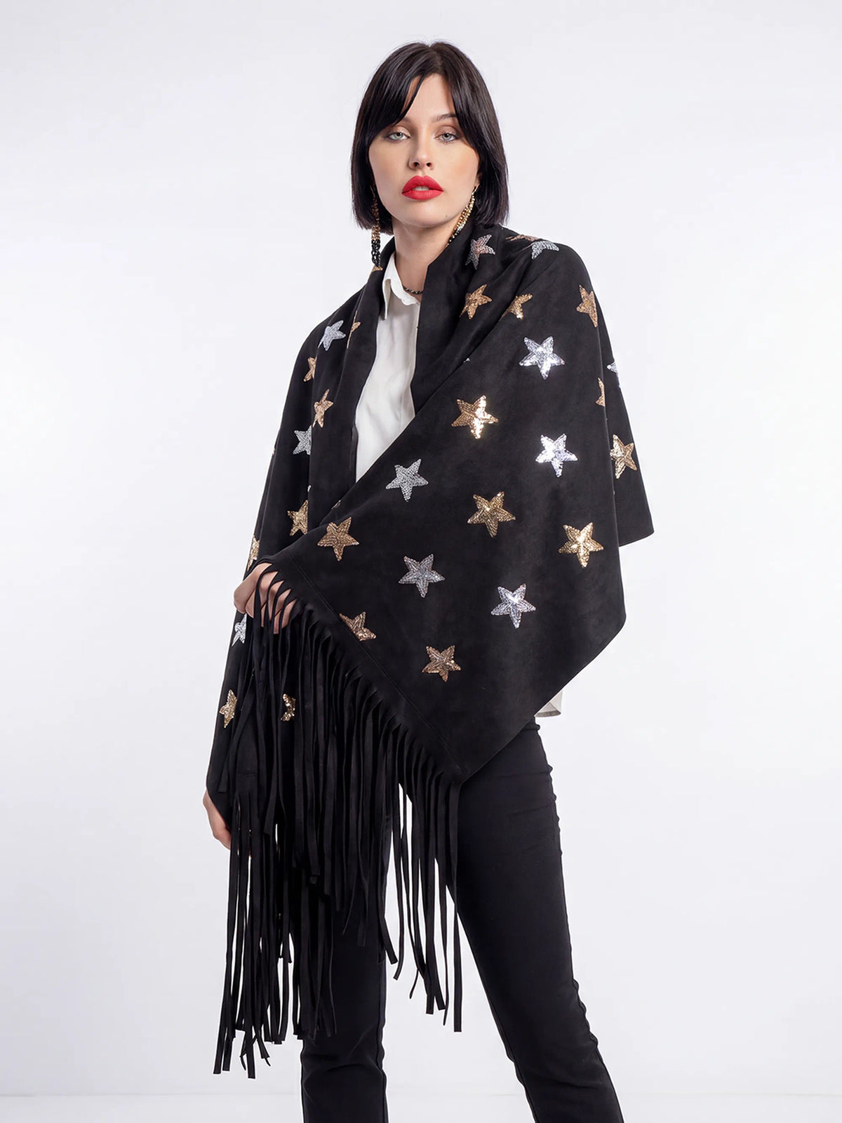 Woman wearing a black star-patterned poncho with fringe on a white background