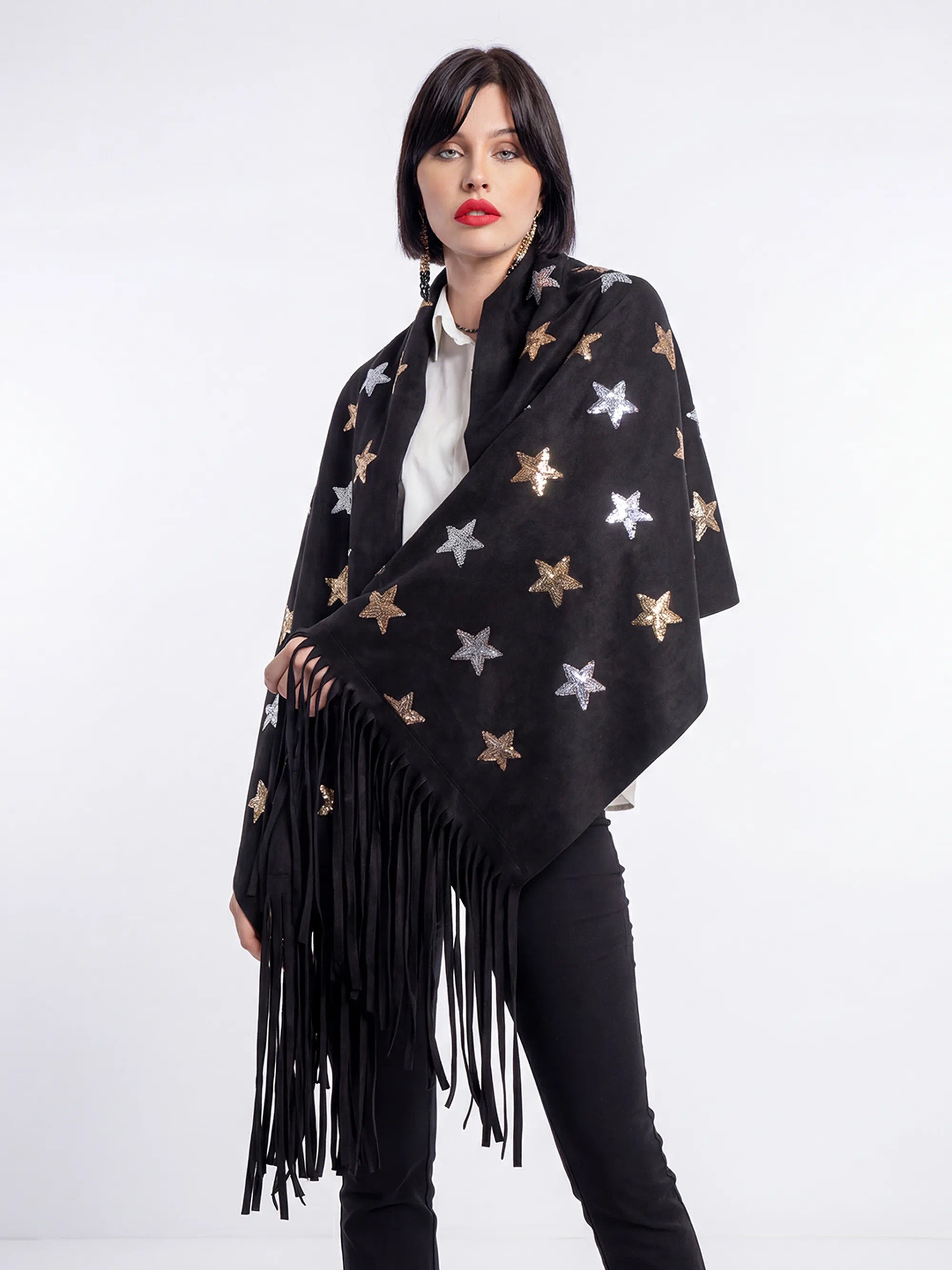 Woman wearing a black star-patterned poncho with fringe on a white background
