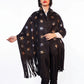Woman wearing a black poncho with star patterns and fringes on a white background