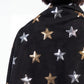 Black scarf with gold and silver star patterns worn by a person on a white background