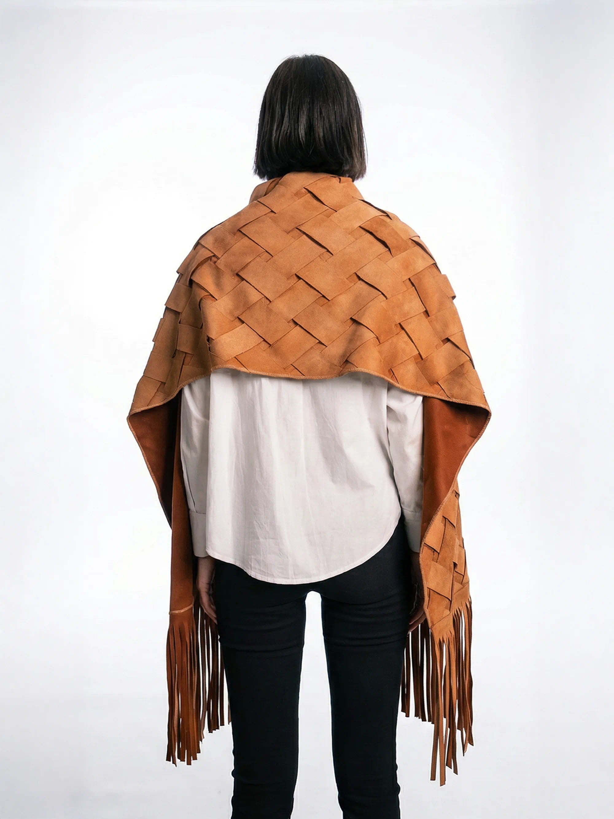 Person wearing a brown woven leather shawl with fringes on a white background