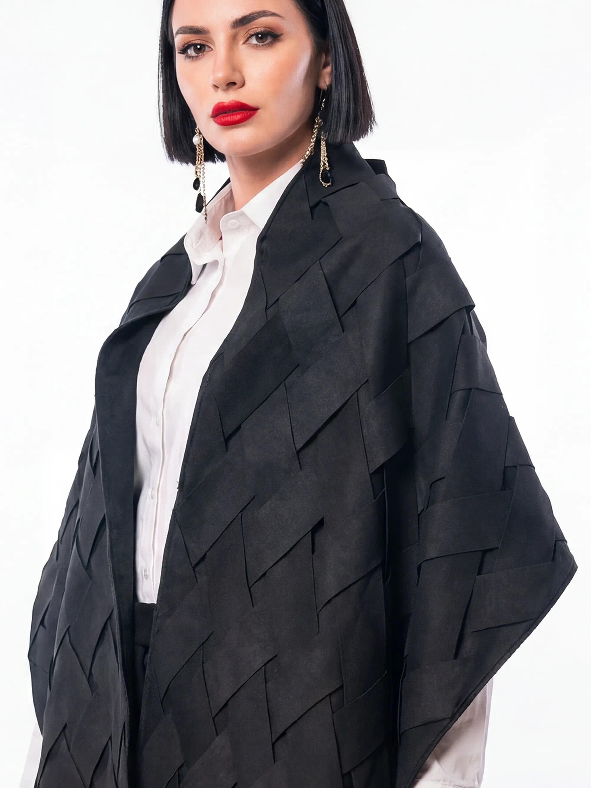 Woman wearing a black layered jacket over a white shirt on a white background